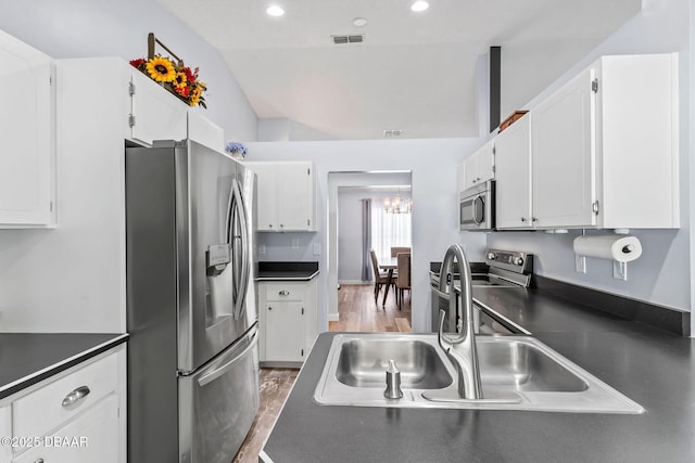 kitchen with a sink, dark countertops, appliances with stainless steel finishes, and white cabinets