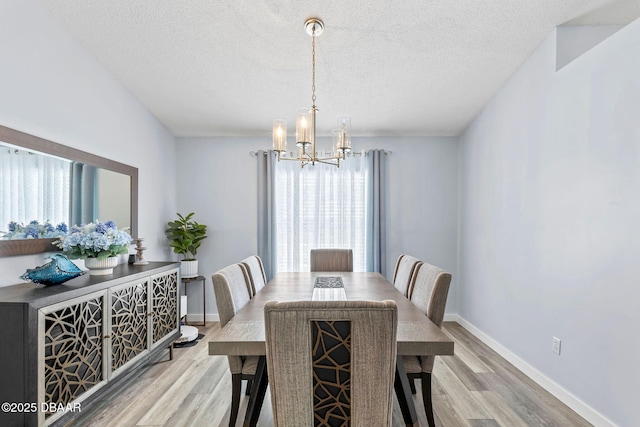 dining space featuring light wood finished floors, plenty of natural light, and an inviting chandelier