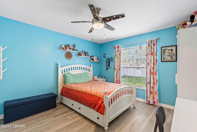 bedroom featuring ceiling fan, wood finished floors, baseboards, and a textured ceiling