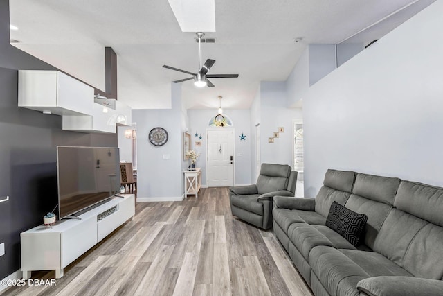 living area with visible vents, high vaulted ceiling, light wood finished floors, baseboards, and ceiling fan