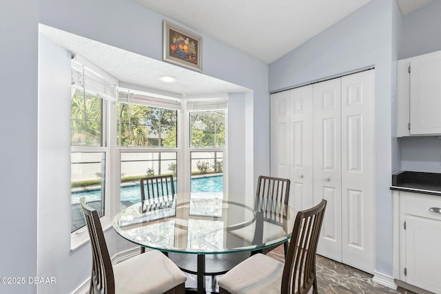 dining area with lofted ceiling and marble finish floor