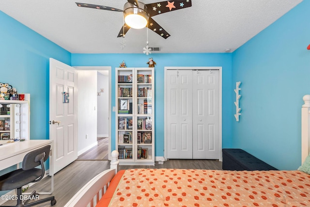 bedroom featuring visible vents, a ceiling fan, a textured ceiling, wood finished floors, and a closet