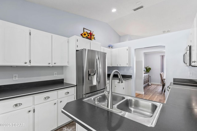 kitchen featuring visible vents, a sink, vaulted ceiling, appliances with stainless steel finishes, and dark countertops