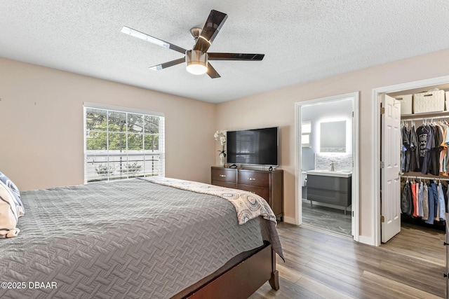 bedroom with ensuite bathroom, a textured ceiling, wood finished floors, a closet, and a spacious closet