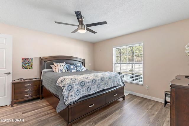 bedroom featuring a ceiling fan, wood finished floors, baseboards, and a textured ceiling