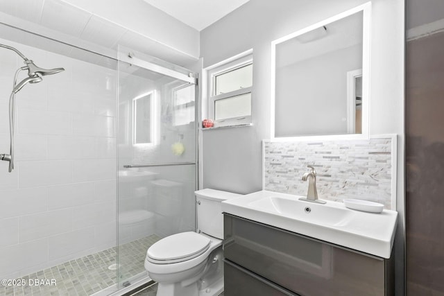 bathroom with tasteful backsplash, a shower stall, toilet, and vanity