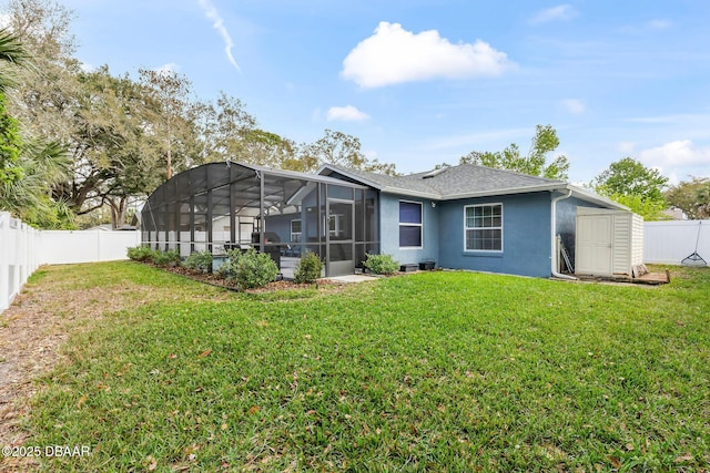 back of property with stucco siding, a yard, a fenced backyard, an outbuilding, and a storage unit