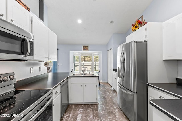 kitchen with dark countertops, appliances with stainless steel finishes, and white cabinetry