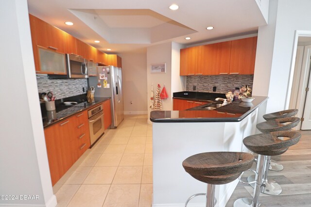 231 Riverside Dr Unit 1106-1, Holly Hill, FL 32117 - kitchen with appliances with stainless steel finishes, dark countertops, brown cabinetry, a kitchen bar, and recessed lighting