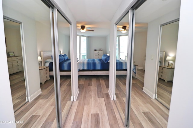 bedroom featuring ceiling fan, light wood-type flooring, and two closets