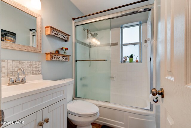 full bathroom featuring shower / bath combination with glass door, vanity, toilet, and backsplash