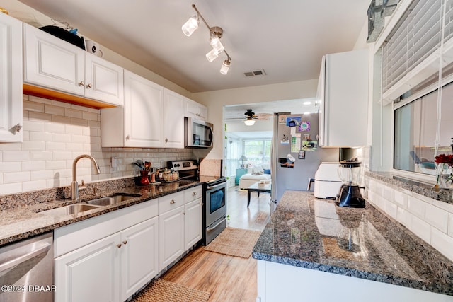 kitchen featuring white cabinets, light hardwood / wood-style flooring, sink, backsplash, and appliances with stainless steel finishes