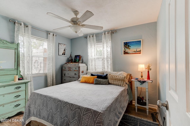 bedroom featuring hardwood / wood-style floors, ceiling fan, and multiple windows