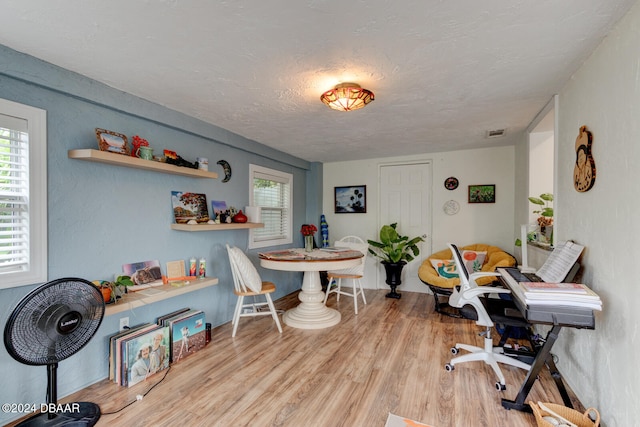 home office with light hardwood / wood-style floors and a textured ceiling