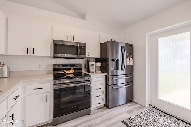 kitchen featuring white cabinets, stainless steel appliances, a healthy amount of sunlight, and vaulted ceiling