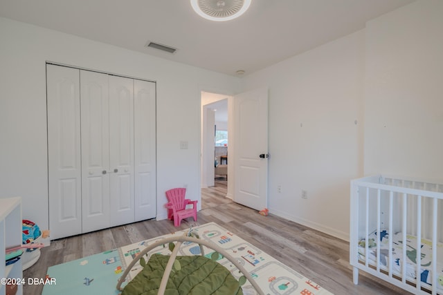 bedroom with a closet, light wood-type flooring, and a crib