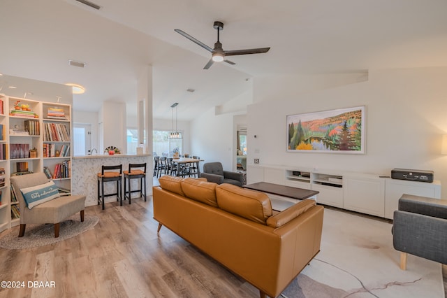 living room featuring vaulted ceiling, ceiling fan, and light hardwood / wood-style flooring