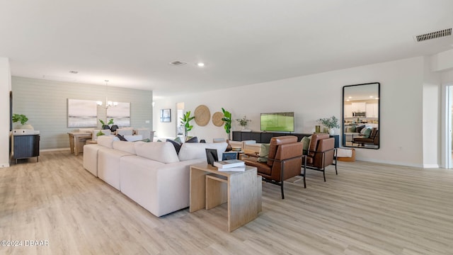 living room featuring light hardwood / wood-style flooring, a healthy amount of sunlight, and a notable chandelier