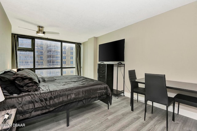 bedroom featuring ceiling fan, expansive windows, a textured ceiling, and light hardwood / wood-style flooring