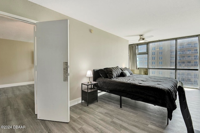 bedroom with ceiling fan, expansive windows, and hardwood / wood-style flooring