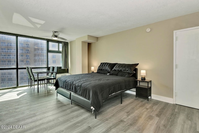 bedroom featuring ceiling fan, a wall of windows, a textured ceiling, and light hardwood / wood-style flooring