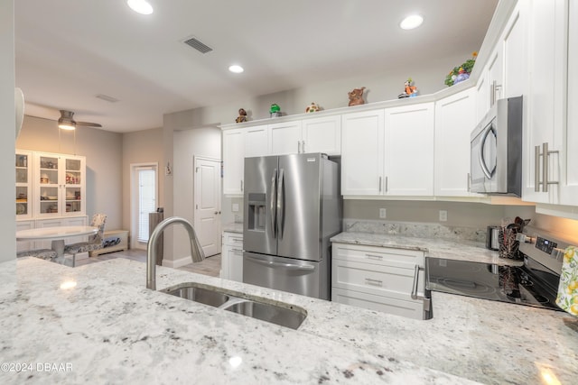 kitchen featuring white cabinetry, sink, ceiling fan, stainless steel appliances, and light stone counters