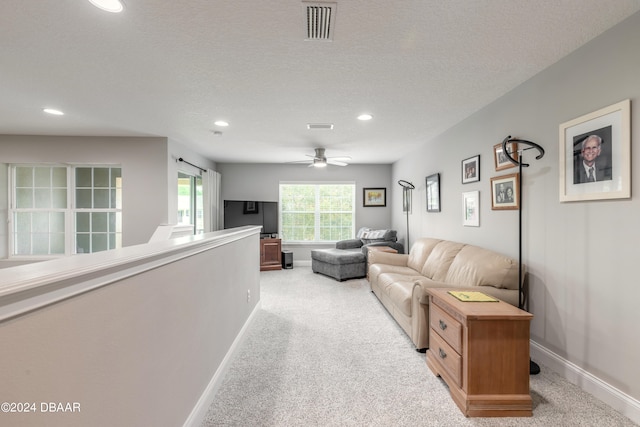 carpeted living room with ceiling fan and a textured ceiling