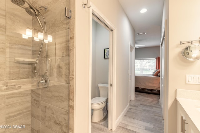 bathroom with hardwood / wood-style floors, vanity, a shower with door, and toilet