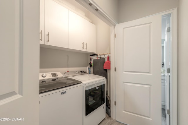 laundry room featuring separate washer and dryer, cabinets, and light hardwood / wood-style floors