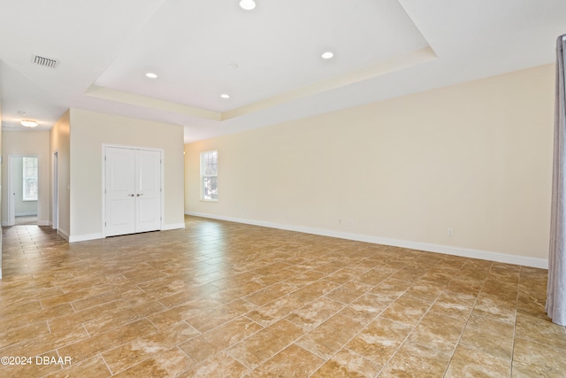 unfurnished room with a wealth of natural light and a raised ceiling