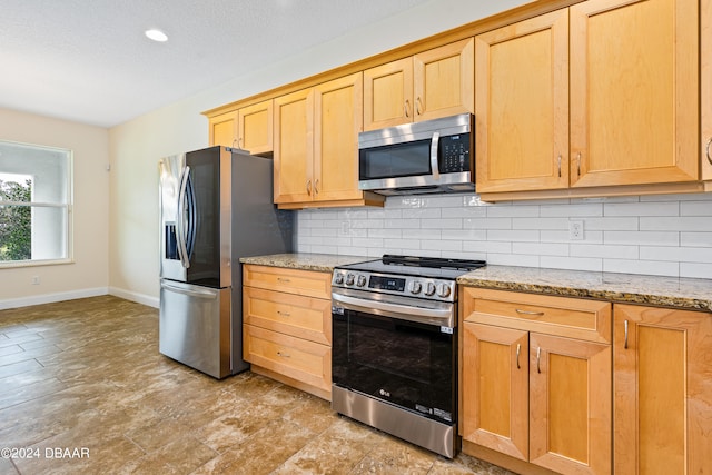 3651 Pini Ave, New Smyrna Beach, FL 32168 - kitchen with backsplash, a textured ceiling, light stone counters, and appliances with stainless steel finishes