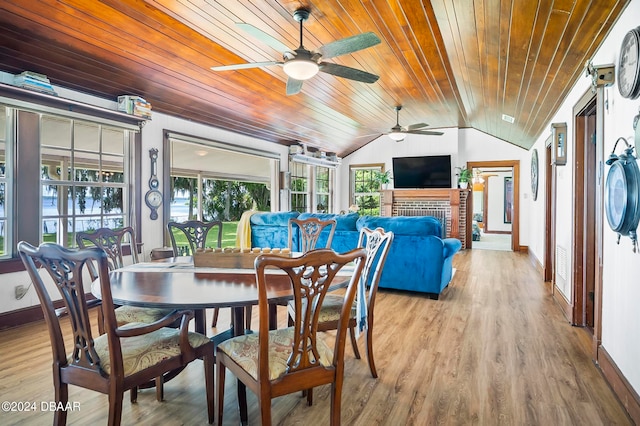 dining area featuring a fireplace, light hardwood / wood-style floors, wood ceiling, and vaulted ceiling