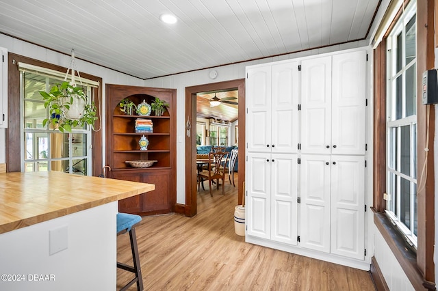 kitchen with white cabinets, light hardwood / wood-style floors, a kitchen breakfast bar, and butcher block countertops