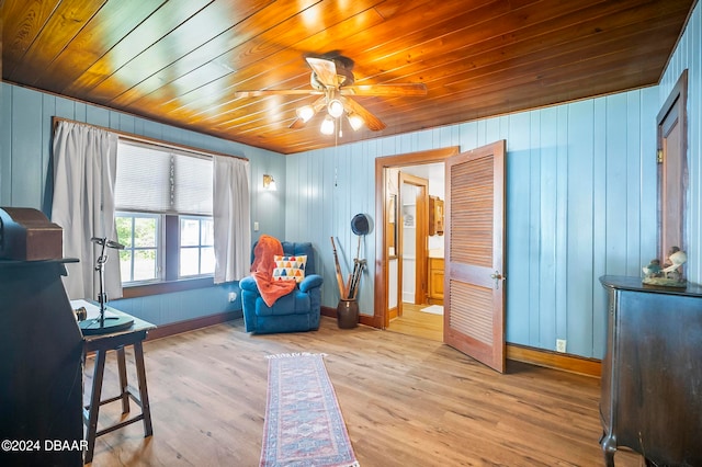 sitting room with wood walls, ceiling fan, wooden ceiling, and light hardwood / wood-style floors