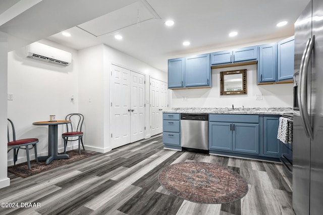 kitchen featuring dark hardwood / wood-style floors, blue cabinets, a wall mounted AC, and stainless steel appliances