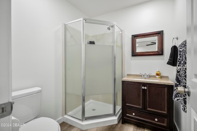 bathroom featuring toilet, vanity, an enclosed shower, and hardwood / wood-style flooring