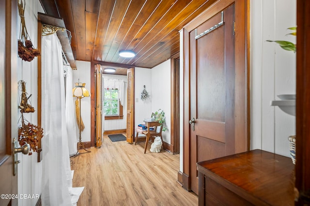 hallway featuring wood walls, light wood-type flooring, and wood ceiling