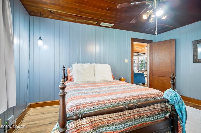 bedroom featuring wood walls, light hardwood / wood-style floors, ceiling fan, and wooden ceiling