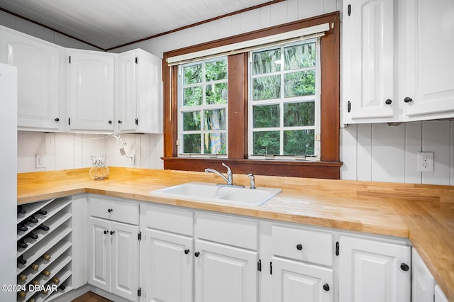 kitchen featuring white cabinets, butcher block countertops, and sink