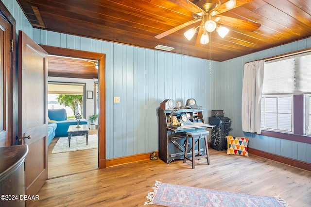 interior space with wood walls, wood ceiling, ceiling fan, and light hardwood / wood-style flooring