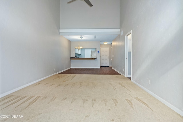 unfurnished living room with carpet flooring, a towering ceiling, and a chandelier