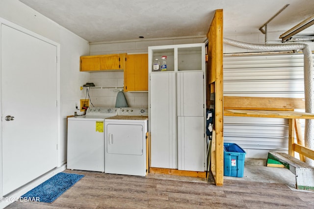 laundry area featuring separate washer and dryer, light hardwood / wood-style flooring, and cabinets