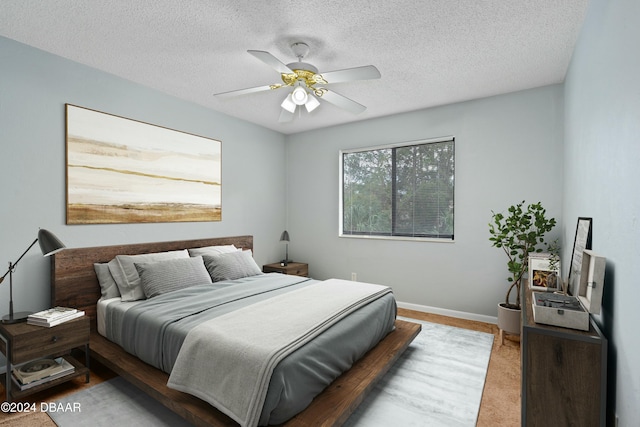 bedroom with ceiling fan, carpet floors, and a textured ceiling