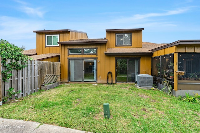 rear view of house featuring central AC, a sunroom, and a yard