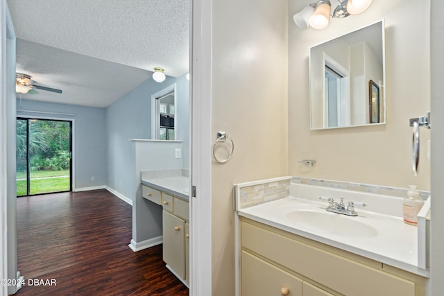 bathroom with ceiling fan, vanity, wood-type flooring, and a textured ceiling