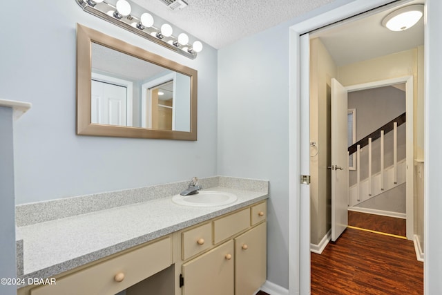 bathroom with hardwood / wood-style floors, vanity, and a textured ceiling