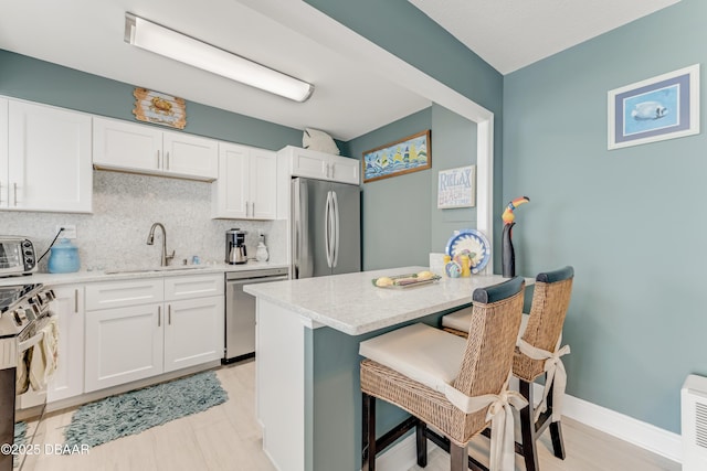 2800 N Atlantic Ave Unit 515, Daytona Beach, FL 32118 - kitchen featuring stainless steel appliances, a sink, backsplash, a kitchen breakfast bar, and white cabinetry
