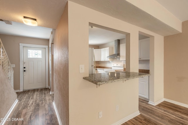 108 Mitchell Pl, Daytona Beach, FL 32118 - kitchen featuring wall chimney exhaust hood, white appliances, wood finished floors, white cabinets, and a kitchen bar