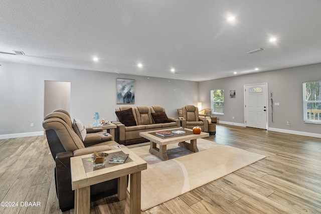 living room with a healthy amount of sunlight, light hardwood / wood-style floors, and a textured ceiling