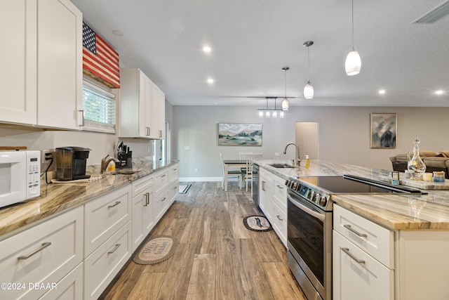 kitchen with light hardwood / wood-style floors, sink, stainless steel range with electric cooktop, white cabinetry, and decorative light fixtures